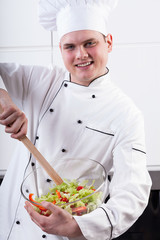 Cheerful chef mixing salad