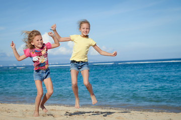happy little girls jumping on beach