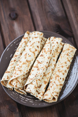 Glass plate with rolled stuffed pancakes, vertical shot