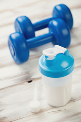 Shaker with protein, plastic dumbbells and a measuring scoop