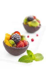 Fruit salad in chocolate cups on white background