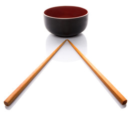 An empty bowl with a pair of chopsticks over white background