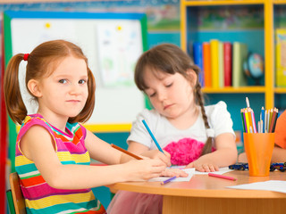 Two cute little girls drawing at school