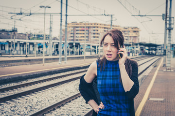 Pretty girl talking on phone along the tracks