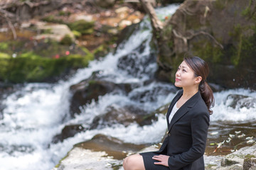 自然の中でリラックスするアジアのスーツの女性