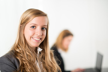 Cheerful young business woman standing up in the office