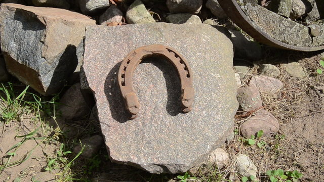 hand puts old iron horseshoes on large flat stone