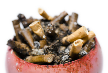 A pile of cigarette butts in old, rusty, red ashtray