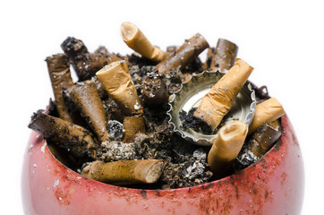 A pile of cigarette butts in old, rusty, red ashtray