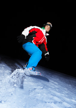 Young snowboarder sliding at night
