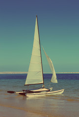 sailing catamaran on beach - vintage retro style