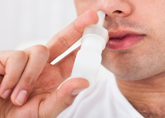 Man Spraying Drops In Nose