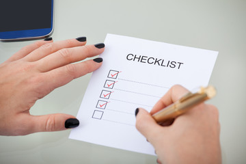 Businesswoman With Checklist At Desk