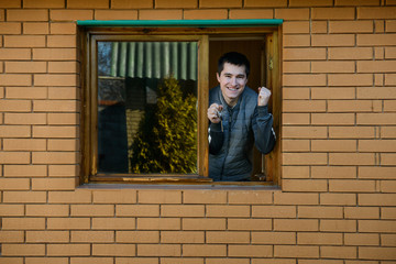 Fototapeta na wymiar Happy man showing keys from the window of his new house