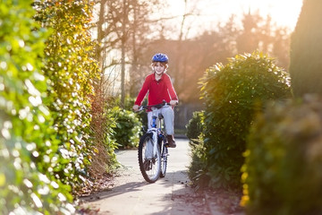 Naklejka premium Happy smiling teenager boy riding his bike on sunset