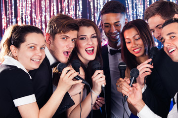 Friends Singing Into Microphones At Karaoke Party