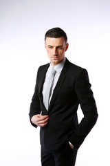 Pensive businessman buttoning his jacket on a gray background