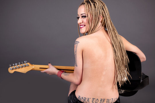beautiful punk girl with lots of tattoos posing with guitar