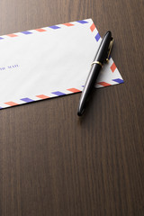 木目の背景にエアメールと万年筆