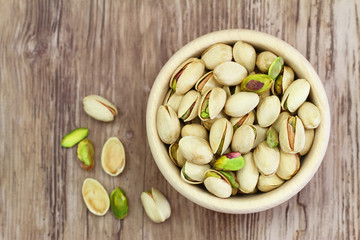 Pistachio nuts in wooden bowl with copy space