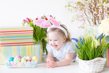 Fototapeta na wymiar Little toddler girl with rabbit's ears next basket of eggs