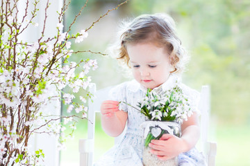 Fototapeta premium Beautiful toddler girl in white dress sitting in white room