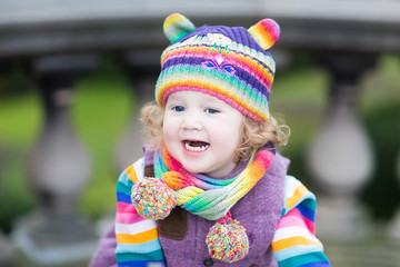 Portrait of a happy toddler girl in striped colorful knitted hat