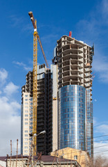 Fototapeta na wymiar Wysokie budynki w trakcie budowy z d¼wigami na tle błękitnego nieba