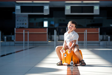 Cute little boy with orange suitcase at airport