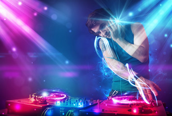 Energetic Dj mixing music with powerful light effects