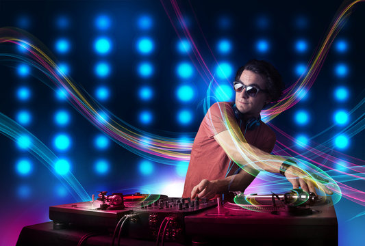 Young Dj mixing records with colorful lights