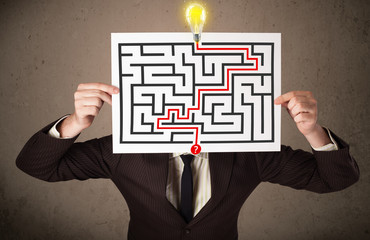 Businessman holding a paper with a labyrinth on it in front of h