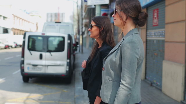 Businesswoman crossing street and talking, steadycam shot