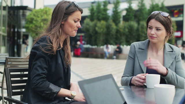 Businesswomen drinking coffee and chatting in street cafe, stead
