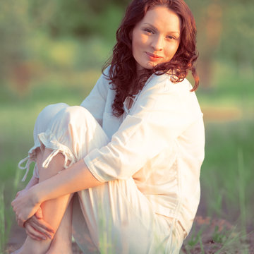 Young woman practicing yoga on the lawn at sunset