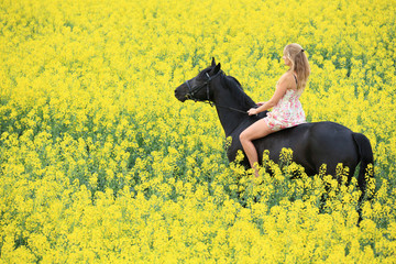 young woman riding on a black horse