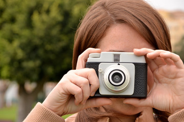 Young woman taking pictures with an old camera in the park