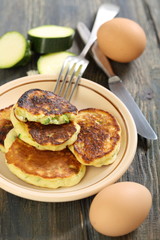 Zucchini fritters and fork on a plate.
