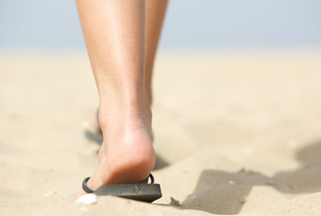 Feet walking in flip flops on beach