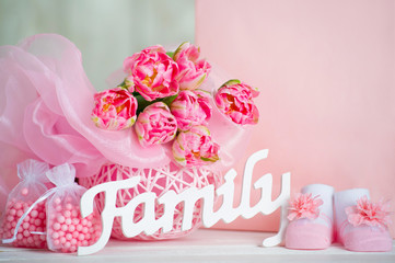 Pink tulips, baby shoes and family sign
