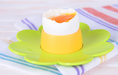 Boiled egg in egg cup on table close-up