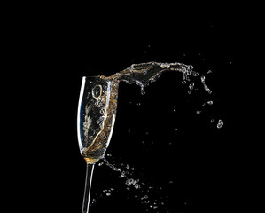 Glass of champagne with splash, on black background