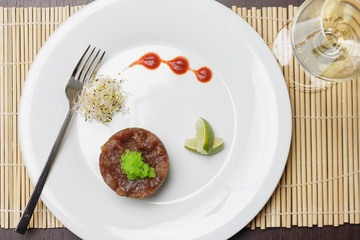 Salmon with tartar sauce and lime on simple white plate