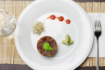 Salmon with tartar sauce and lime on simple white plate