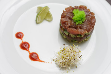 Salmon with tartar sauce and lime on simple white plate