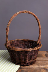 Empty wicker basket on wooden table, on dark background