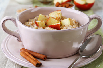 Tasty oatmeal with apples and cinnamon on table close up