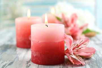 Beautiful candles with flowers on wooden background