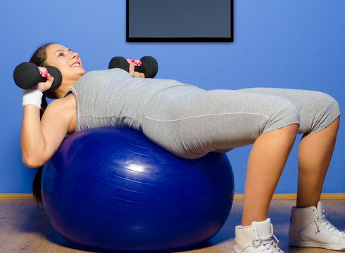 Smiling girl exercising with dumbbells