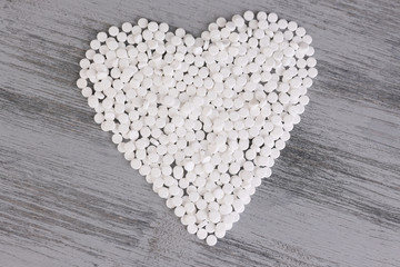 Heart of pills on wooden background